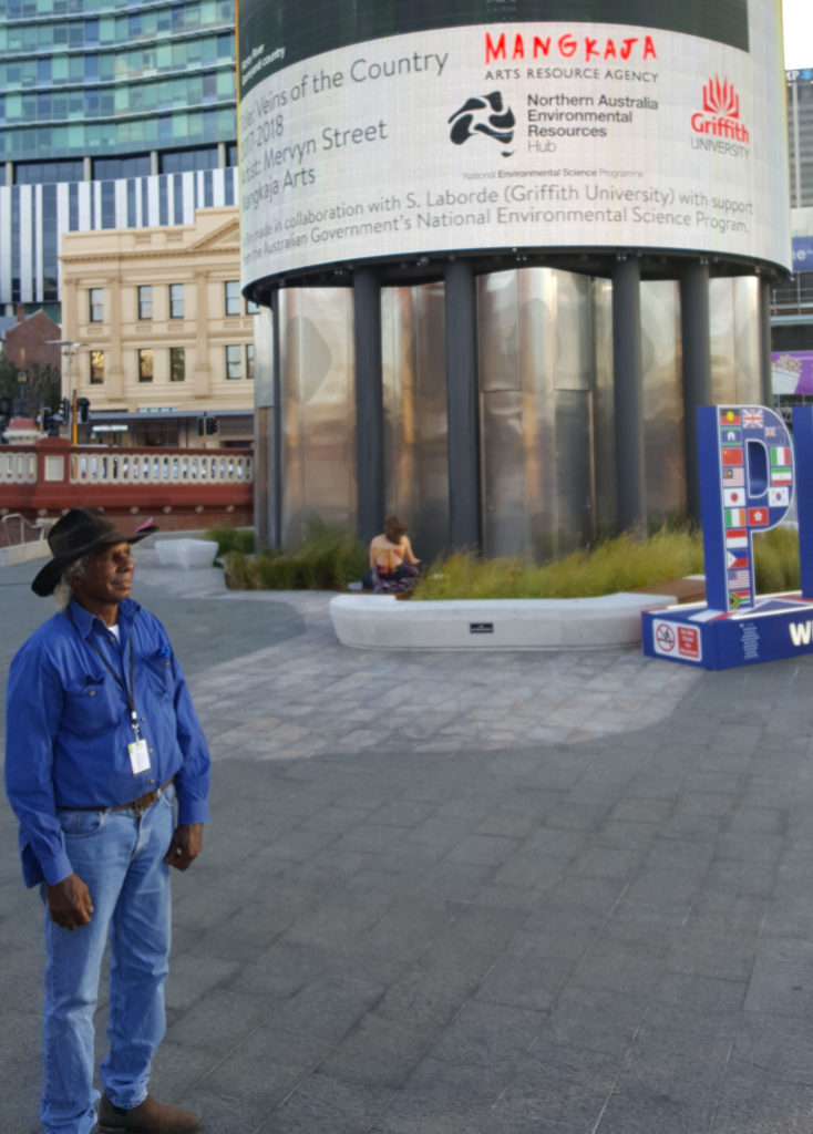 Gooniyandi man, Mervyn Street, in front of Yagan Square big screen in Perth showing his short film