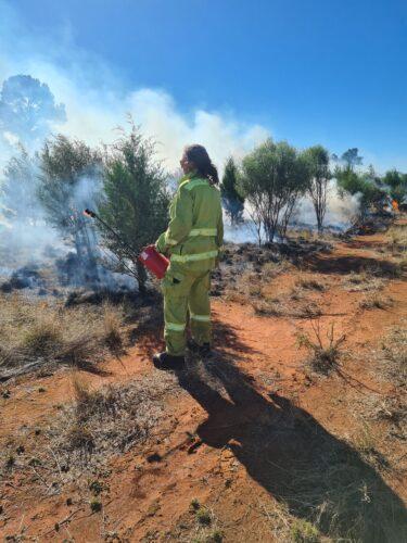 A woman holds a fire bug, while doing a cultural burn 